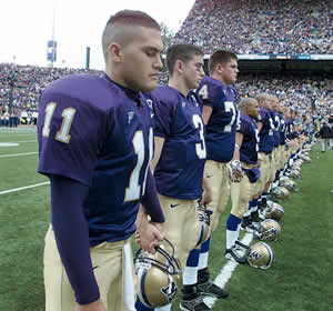 Quarterback Marques Tuiasosopo (11) holds hands with teammates before the 2000 UW-Arizona game as they pray for injured teammate Curtis Williams. Photo by Steve Ringman, copyright 2000 Seattle Times.